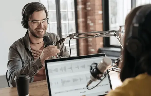 Two people recording internal company podcasts, with microphones and headphones.